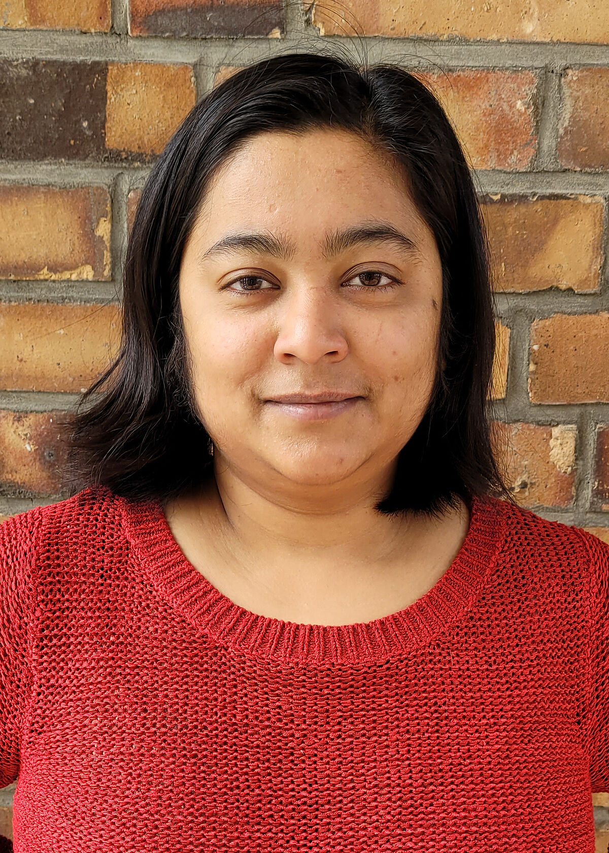 Portrait Mousumi Hazarika in front of a stone wall